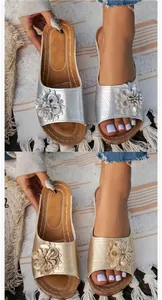 Side-by-side comparison of silver and gold floral wedge slide sandals on a beach mat