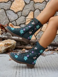 Detailed side view of floral embroidered mid-calf boots with lacing and side zipper