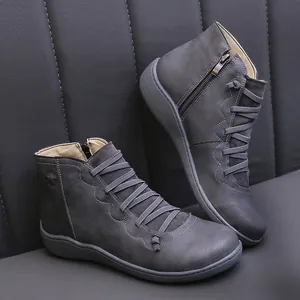 Detail view of grey faux leather women's ankle boots with side zipper and wavy trim
