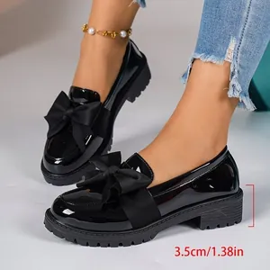 Detail view of black patent leather loafers with large bow and 3.5cm platform heel