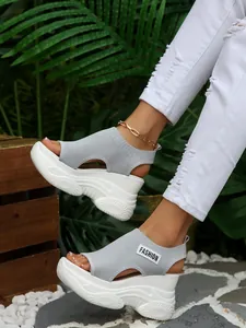 Gedetailleerd zijaanzicht van grijze fly-knit platformsandalen met hoge witte sportzolen.