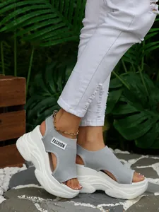 Detail van grijze fly-knit wedge sandalen met dik wit platform en open teen ontwerp.