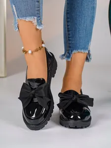 Elegant black patent leather loafers with oversized bow detail and thick platform sole