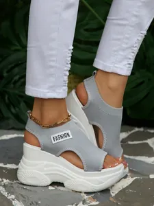 Close-up van grijze fly-knit platformsandalen met witte zool en modieus label erop