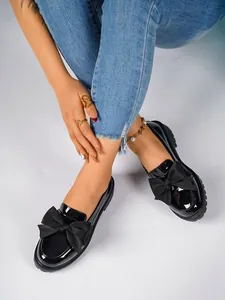 Detail shot of black patent leather loafers with an elegant oversized bow decoration