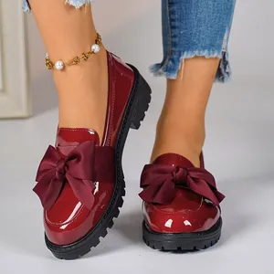 Elegant wine red patent leather loafers with oversized burgundy bows and thick soles.