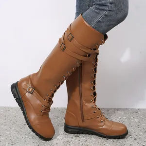 Detail view of brown lace-up knight boots featuring buckle straps and low flat heel