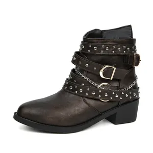 Detalle de botines de cuero marrón para mujer con tachuelas, hebillas y cadena de plata