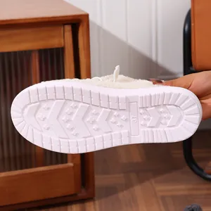 Close-up detail of the durable non-slip white sole on a warm fuzzy cream winter slipper