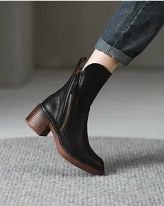 Side view of vintage black leather mid-calf boots featuring a block heel and side zipper.