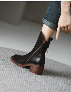 Close-up of black retro leather mid-calf Martin boots with side zipper and chunky heel.