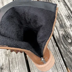 Close-up shot of black faux fur lining and metallic zipper detail inside brown women boots.