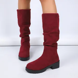 Close-up of stylish red suede slouchy boots with chunky heels and textured rubber soles