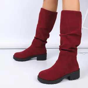 Close-up of wine red suede slouchy boots featuring chunky low heels and fold design