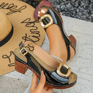 Detailed view of black patent leather peep-toe sandals with elegant gold buckle