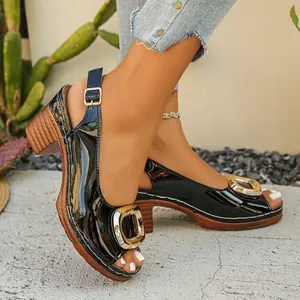 Detailed macro view of black patent leather peep-toe sandals with gold metal buckle