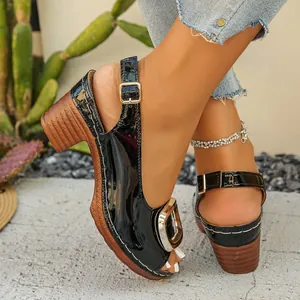Close-up of black patent leather peep-toe sandals with gold buckle and wooden block heel