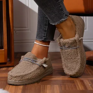 Close-up view of khaki fleece-lined platform loafers worn indoors.