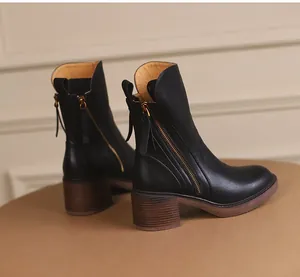 Detailed side view of vintage black mid-calf boots featuring a metal zipper and chunky heel