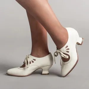 Detail view of cream vintage lace-up pumps with elegant petal cutouts and low heels.