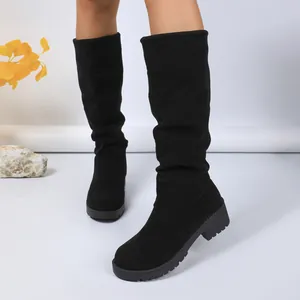 Detailed shot of black suede slouchy boots with chunky heels for winter fashion.