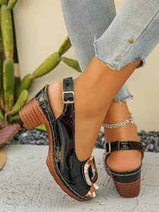Detailed shot of black patent leather chunky heel sandals featuring a metal buckle decor
