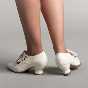 Close-up detail view of vintage cream lace-up high heels with elegant teardrop cutouts on model