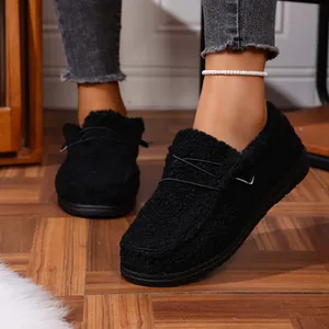 Close-up of black fuzzy winter loafers with thick soles and decorative metal detail