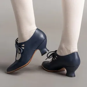 Close-up of vintage navy blue lace-up high heels with elegant hollow-out pattern details.