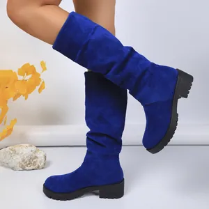 Detailed close-up of stylish blue suede slouchy mid-calf boots with chunky lug sole