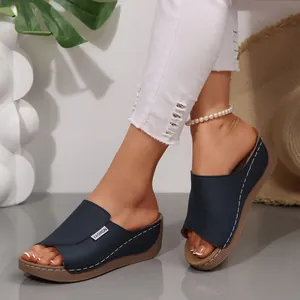 Close-up of navy blue peep-toe wedge sandals featuring a stylish white fashion tag