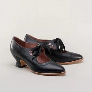 Detail of vintage black leather heels with teardrop cutouts and lace-up front bows.