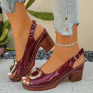 Detail view of stylish burgundy patent leather sandals with gold buckle and chunky heel.