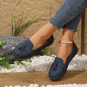 Macro shot of blue suede-style tassel loafers on model with pearl anklet detail