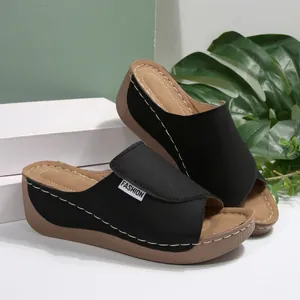 Detail showing black peep-toe wedge slippers with white stitching and platform sole