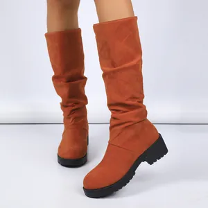 Close-up of stylish orange suede slouchy boots with chunky heels and platform