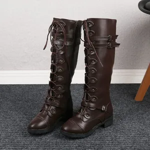 Side view of tall brown lace-up motorcycle boots with buckle details and flat soles