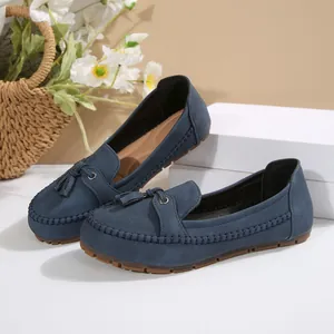 Close-up of blue suede-style loafers with tassel details and stitched edges