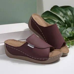 Side detail view of burgundy wedge peep-toe sandals with elegant white decorative stitching