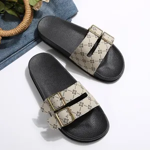 Detailoverzicht van dames slippers met dubbele gesp en monogrampatroon