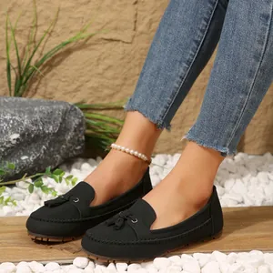 Detailed close-up of black women's tassel loafers styled with denim and pearl anklet