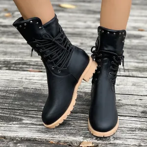 Stylish black women's mid-calf boots with rivets and chunky heel on a rustic wooden deck.