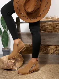 Detail shot of women's western tan suede ankle boots with side zipper and heel