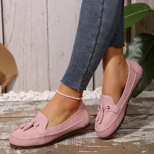 Detailed close-up view of stylish pink suede loafers with decorative tassel details