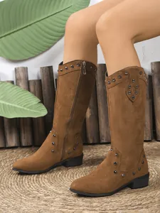 Close-up side view of brown suede western boots with metallic studs and side zipper