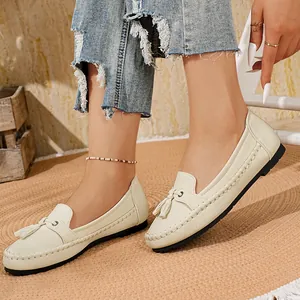 Nahaufnahme von cremefarbenen Damen-Loafers mit Quasten und Handnaht-Details.