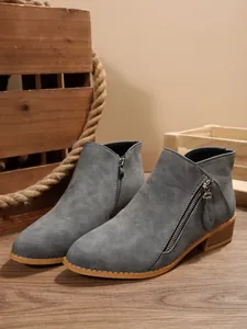 Detail view of grey pointed-toe ankle boots featuring stylish double side zippers.