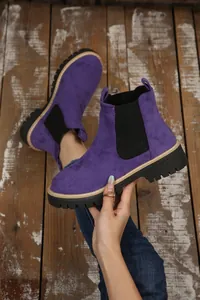 Dettaglio di stivaletti Chelsea in pelle scamosciata viola con suola spessa a carrarmato.