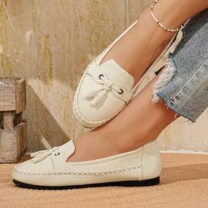 Detailansicht cremefarbener Damen-Loafer mit Quastenschleife und Ziernähten am Fuß.