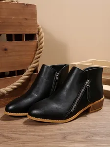 Close-up detail of black pointed toe ankle boots featuring stylish side zipper and block heel.